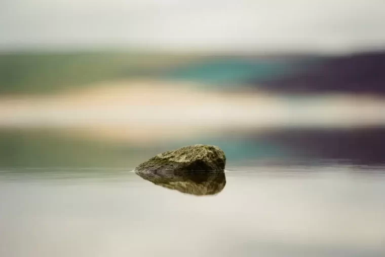 A single weathered stone resting at the edge of still water